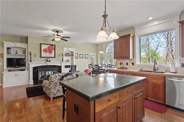kitchen featuring wood finished floors, a center island, a sink, dishwasher, and decorative light fixtures