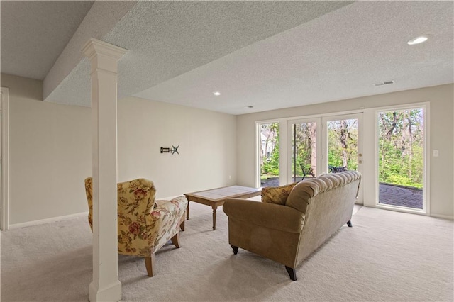 living area with a textured ceiling, a healthy amount of sunlight, and light carpet