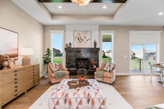 16159 S Kaw St, Olathe, KS 66062 - living area featuring light wood-type flooring, a tray ceiling, baseboards, a fireplace, and recessed lighting