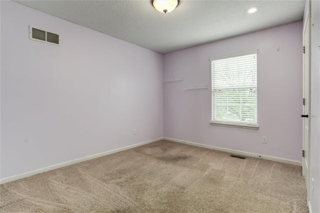 empty room with visible vents, carpet flooring, baseboards, and a textured ceiling