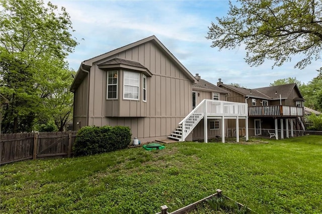 back of property with a fenced backyard, a wooden deck, a lawn, and stairway