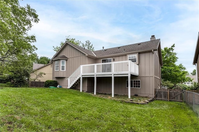 back of property with a deck, stairway, a fenced backyard, a chimney, and a lawn