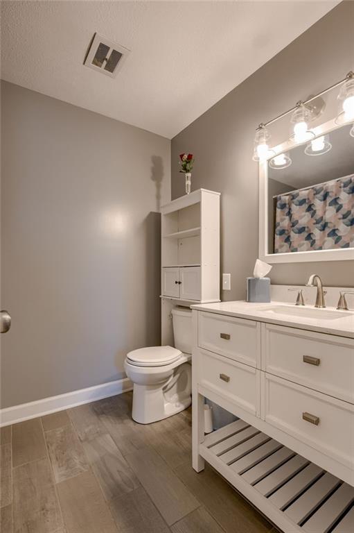 50 N 80th Pl, Kansas City, KS 66111 - bathroom featuring wood finished floors, vanity, toilet, and curtained shower