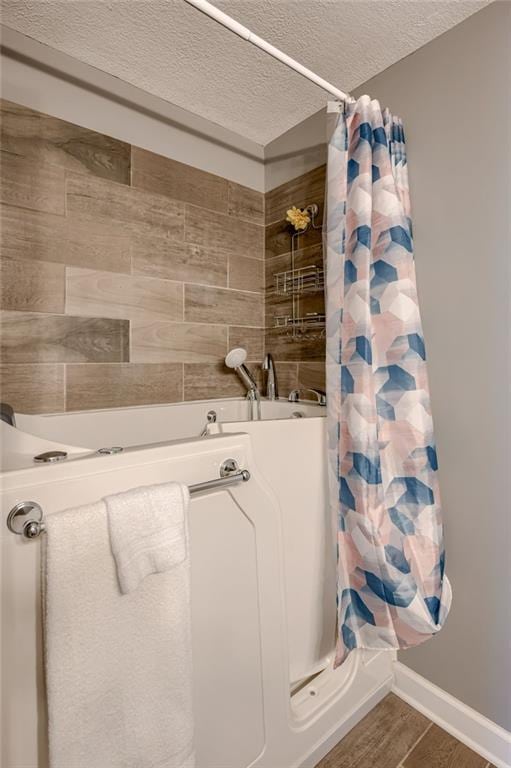 50 N 80th Pl, Kansas City, KS 66111 - bathroom with a textured ceiling, a shower with shower curtain, wood finished floors, and baseboards