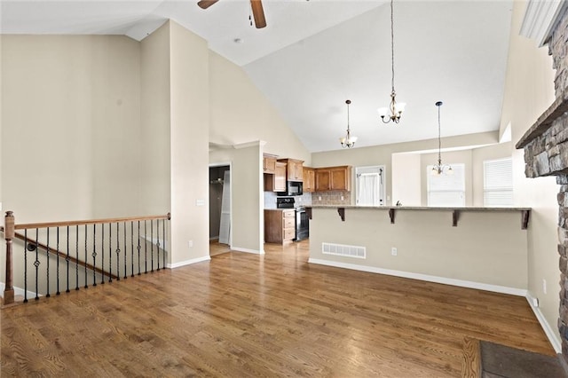 unfurnished living room featuring wood finished floors, visible vents, baseboards, high vaulted ceiling, and ceiling fan with notable chandelier