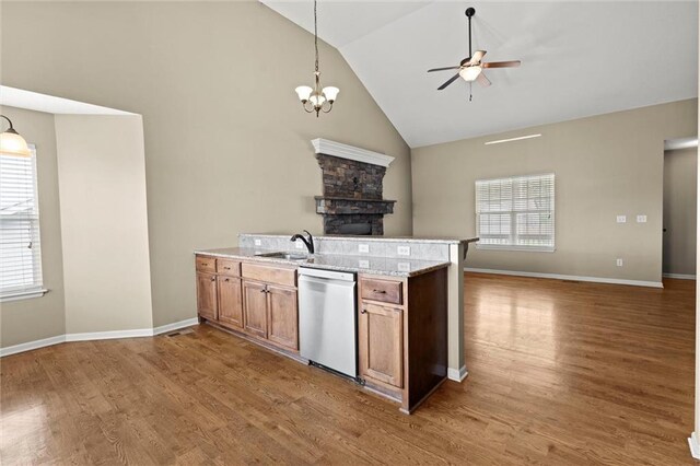 kitchen with ceiling fan with notable chandelier, open floor plan, stainless steel dishwasher, and brown cabinets