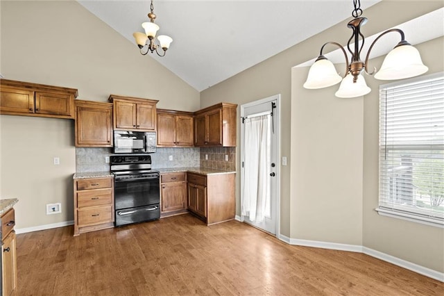 kitchen with tasteful backsplash, brown cabinetry, black appliances, a chandelier, and dark wood-style floors