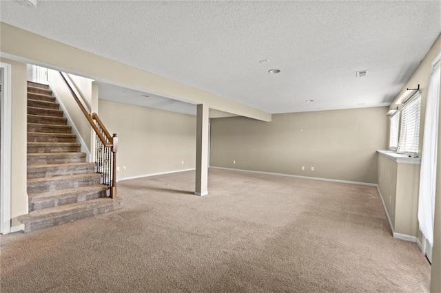 basement with stairway, visible vents, baseboards, a textured ceiling, and light colored carpet
