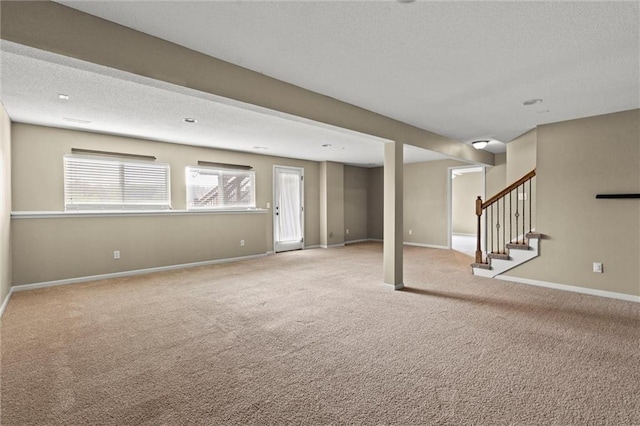 basement featuring carpet floors, a textured ceiling, and stairway