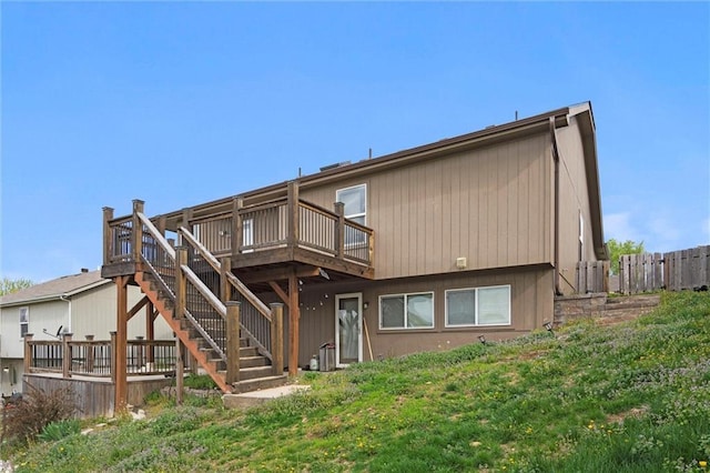 rear view of house featuring a wooden deck, stairway, and fence