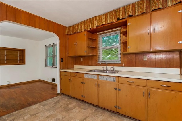 kitchen with open shelves, baseboards, light countertops, a sink, and stone finish flooring
