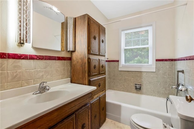 bathroom featuring a tub, toilet, tile walls, and wainscoting