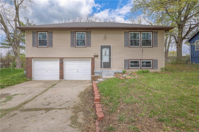 bi-level home with brick siding, a front lawn, driveway, and a garage