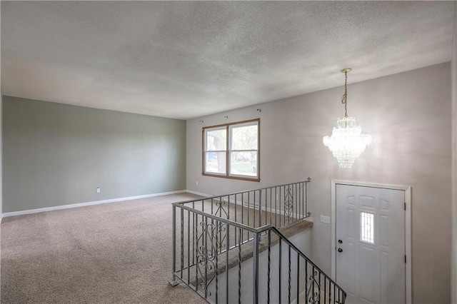 interior space featuring carpet floors, a textured ceiling, baseboards, and a notable chandelier
