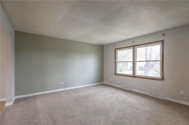 unfurnished room with baseboards, visible vents, a textured ceiling, and carpet flooring