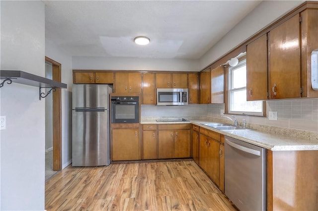 kitchen featuring light countertops, brown cabinets, black appliances, and light wood-style flooring