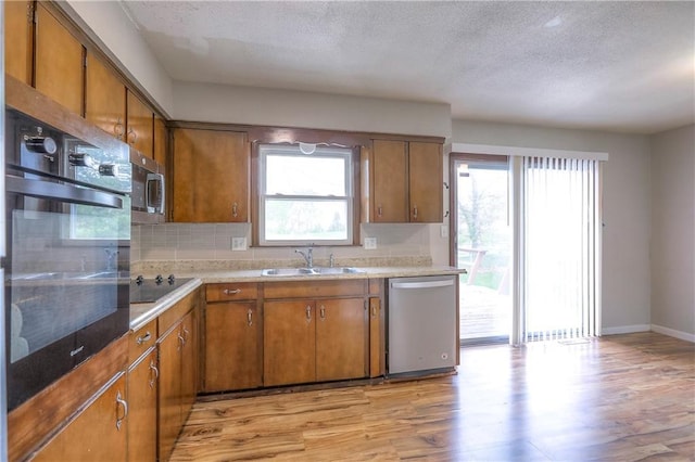 kitchen featuring black appliances, brown cabinets, a sink, and light wood finished floors