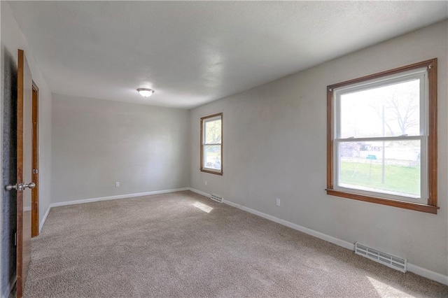 carpeted empty room featuring baseboards and visible vents