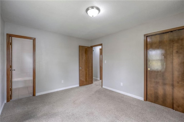 unfurnished bedroom with ensuite bath, baseboards, and carpet flooring