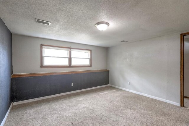 empty room with baseboards, a textured ceiling, visible vents, and carpet