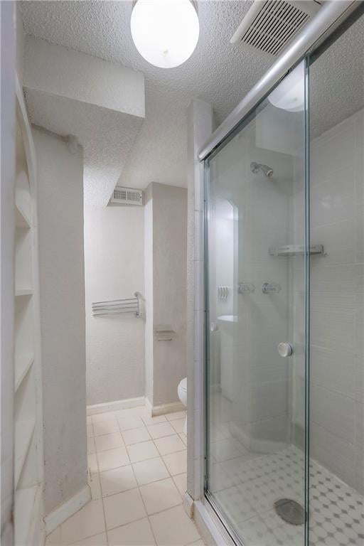bathroom featuring a shower stall, a textured ceiling, and visible vents