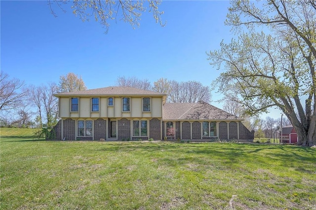 back of house with brick siding and a lawn