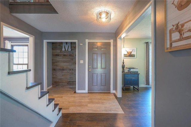 foyer entrance with baseboards, stairway, wood finished floors, and a textured ceiling