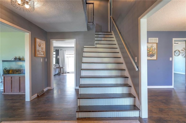 stairway with visible vents, a textured ceiling, and wood finished floors