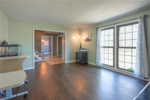 interior space with a textured ceiling, wood finished floors, baseboards, and stairway