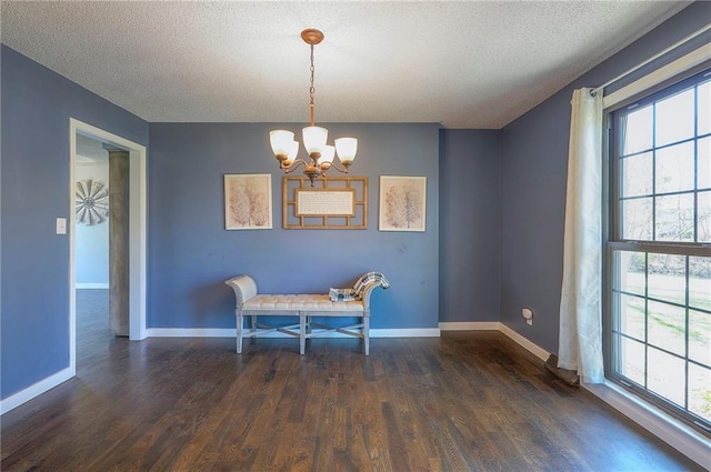 dining room with a chandelier, a textured ceiling, dark wood-style flooring, and plenty of natural light