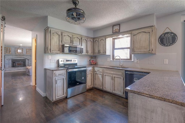 kitchen with a sink, dark wood-style flooring, appliances with stainless steel finishes, a textured ceiling, and backsplash