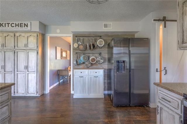kitchen with baseboards, a textured ceiling, visible vents, dark wood finished floors, and stainless steel appliances
