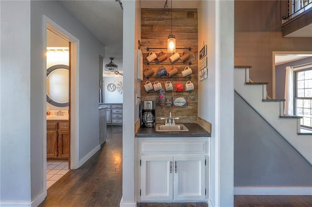 corridor featuring stairs, dark wood-style flooring, baseboards, and a sink