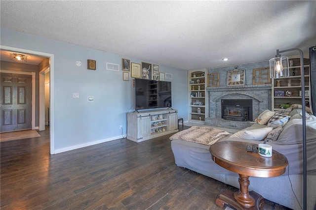 living room with visible vents, baseboards, a brick fireplace, a textured ceiling, and wood finished floors