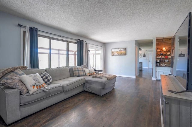 living room featuring dark wood-style floors, a textured ceiling, and baseboards