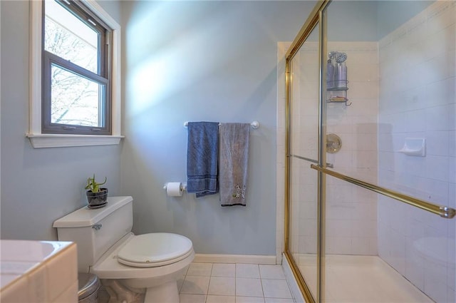 full bath with a shower stall, tile patterned flooring, baseboards, and toilet