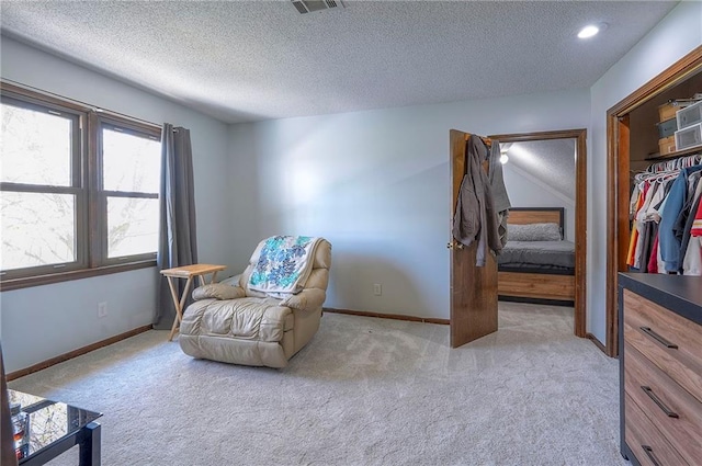 living area featuring baseboards, carpet, and a textured ceiling
