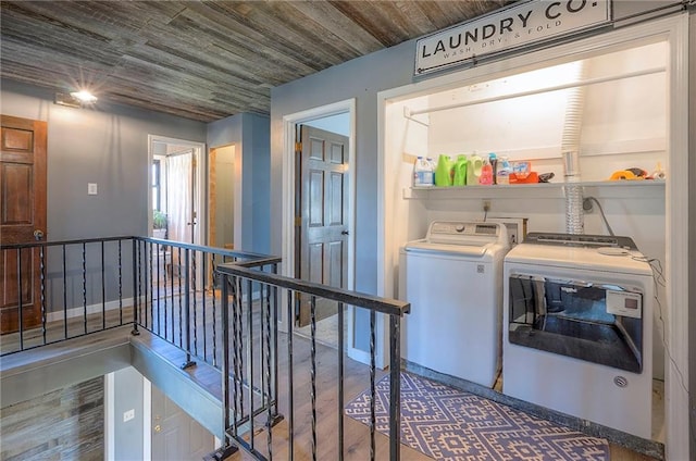clothes washing area with independent washer and dryer, laundry area, wood finished floors, and baseboards
