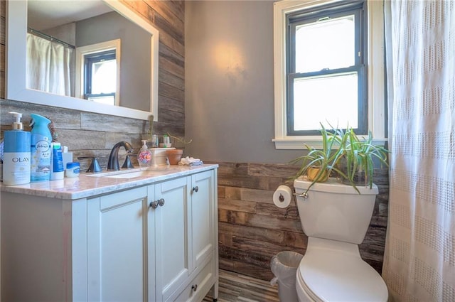 full bath with wood walls, vanity, backsplash, and toilet