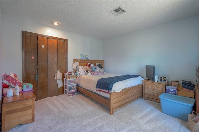 carpeted bedroom featuring a textured ceiling and visible vents