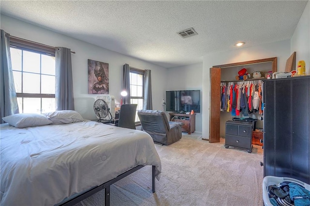 bedroom featuring a closet, light colored carpet, visible vents, and a textured ceiling
