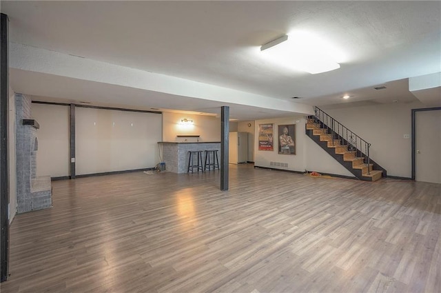 finished below grade area with visible vents, baseboards, wood finished floors, and stairs