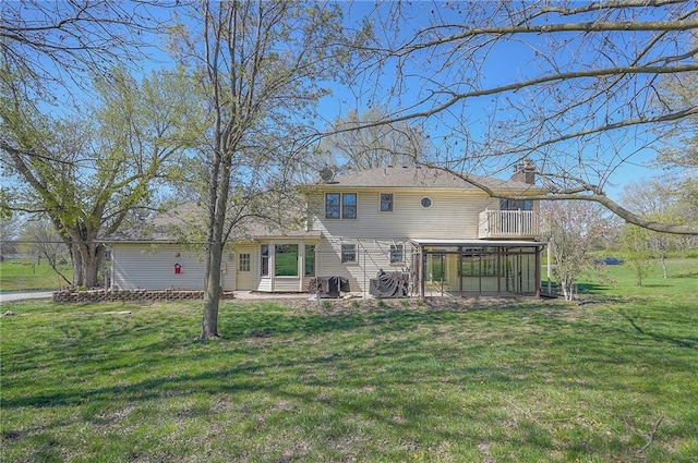 back of house featuring a yard, a sunroom, and a chimney