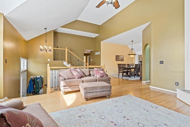 12848 S Rene St, Olathe, KS 66062 - living room featuring wood finished floors, baseboards, high vaulted ceiling, arched walkways, and ceiling fan with notable chandelier