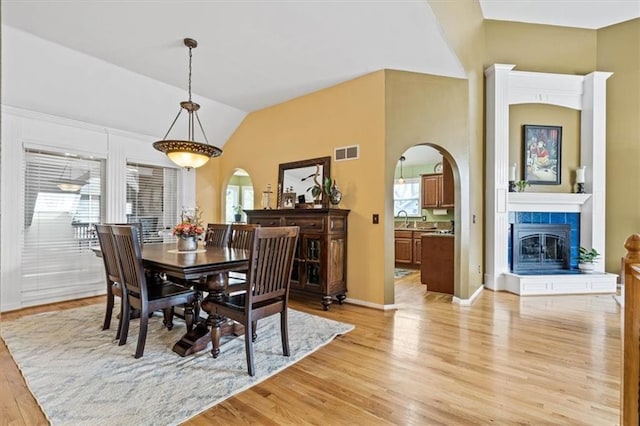 12848 S Rene St, Olathe, KS 66062 - dining area featuring visible vents, a tiled fireplace, arched walkways, light wood finished floors, and lofted ceiling