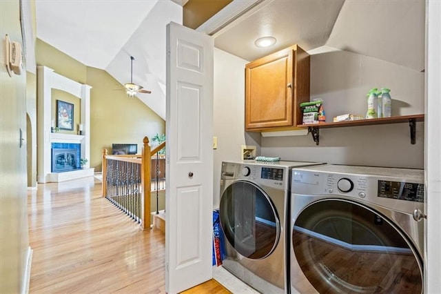 12848 S Rene St, Olathe, KS 66062 - clothes washing area with ceiling fan, washing machine and clothes dryer, a fireplace, light wood-type flooring, and cabinet space