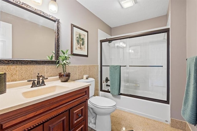 12848 S Rene St, Olathe, KS 66062 - full bathroom with tile walls, speckled floor, bath / shower combo with glass door, vanity, and toilet