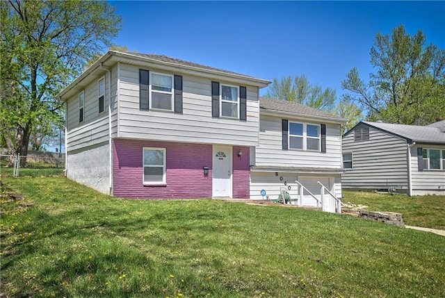 tri-level home with a garage, a front lawn, and fence