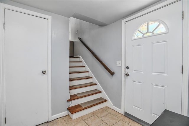 foyer entrance featuring baseboards, stairs, and light tile patterned floors