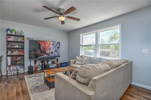living area with wood finished floors, a ceiling fan, and baseboards